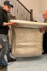 Professional movers from BMOVED carrying heavy armchair up stairs safely