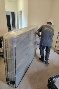 Professional movers from BMOVED carrying wrapped furniture through residential hallway