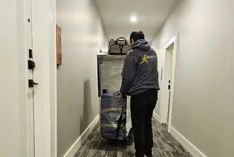 BMOVED professional mover carefully transporting stacked boxes through narrow hallway in Toronto home