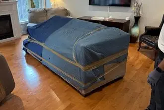 Bed frame wrapped in blue protective blankets by BMOVED professional moving team